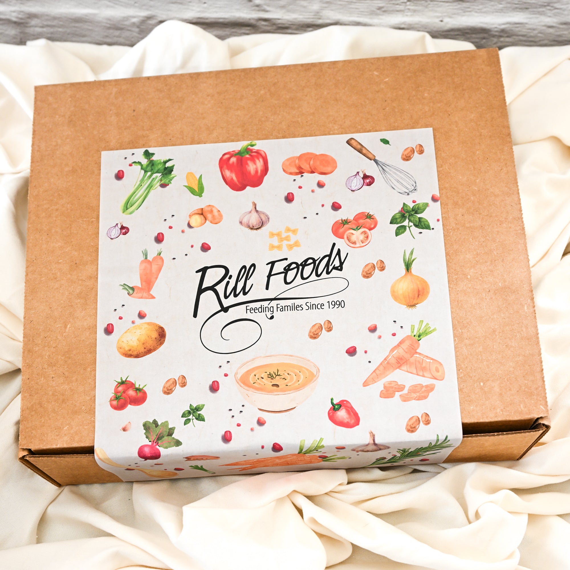 Box with 'Rill Foods' label featuring food illustrations on a white fabric background