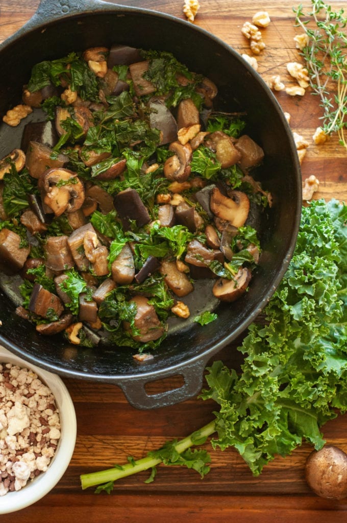 This image depicts a frying pan full of the kale, mushrooms, and other ingredients used for the recipe.