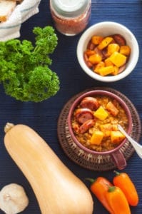 This image displays a bowl of prepared Lion's Den Red Lentil Soup, topped with butternut squash and sausage.